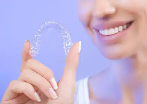 woman holding clear aligner before wearing Invisalign aligners